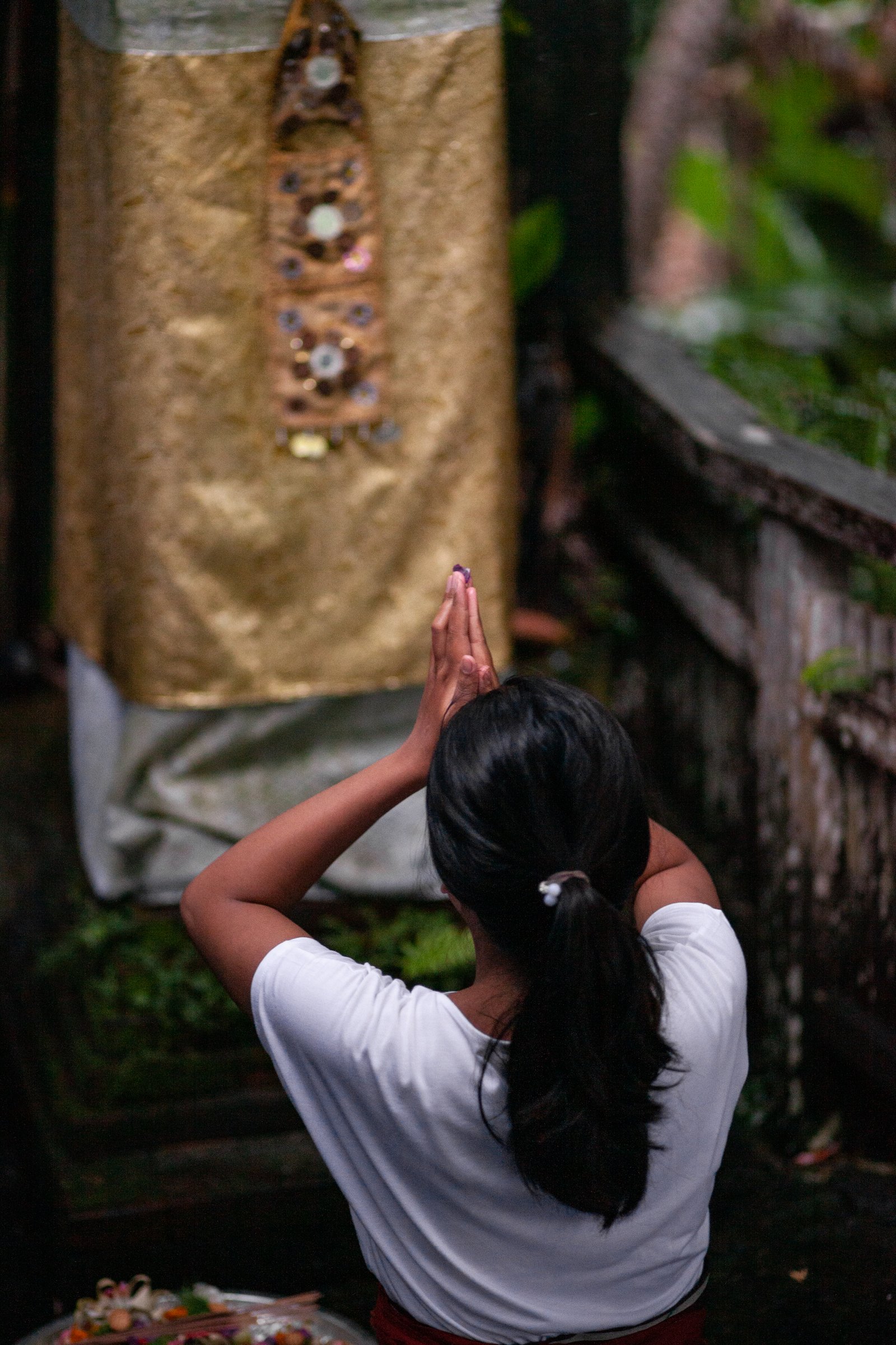 A woman offering a prayer at a Balinese shrine
